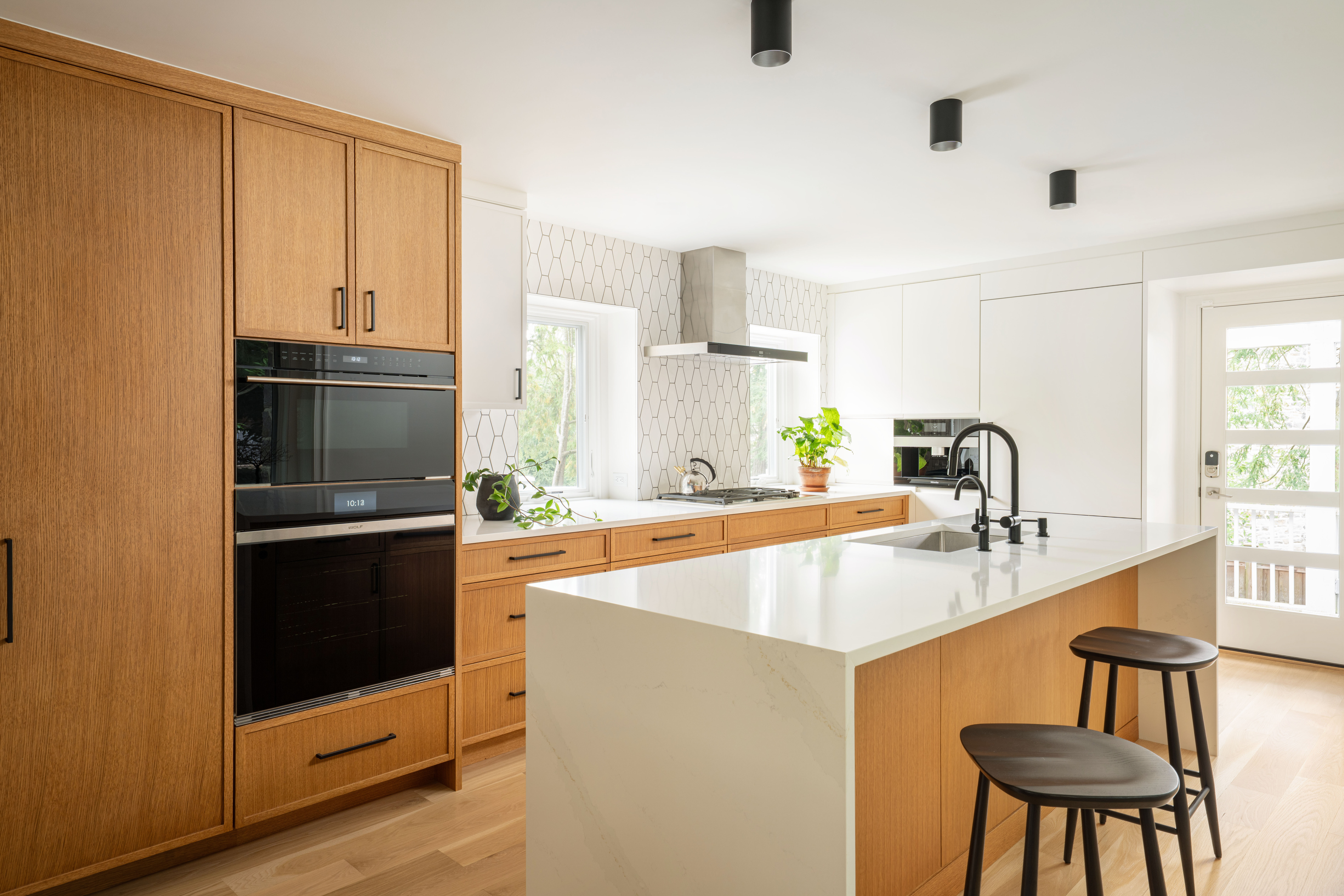 Modern Philadelphia kitchen remodel with custom white and oak cabinetry, quartz countertops, and black fixtures by Bellweather Design-Build.