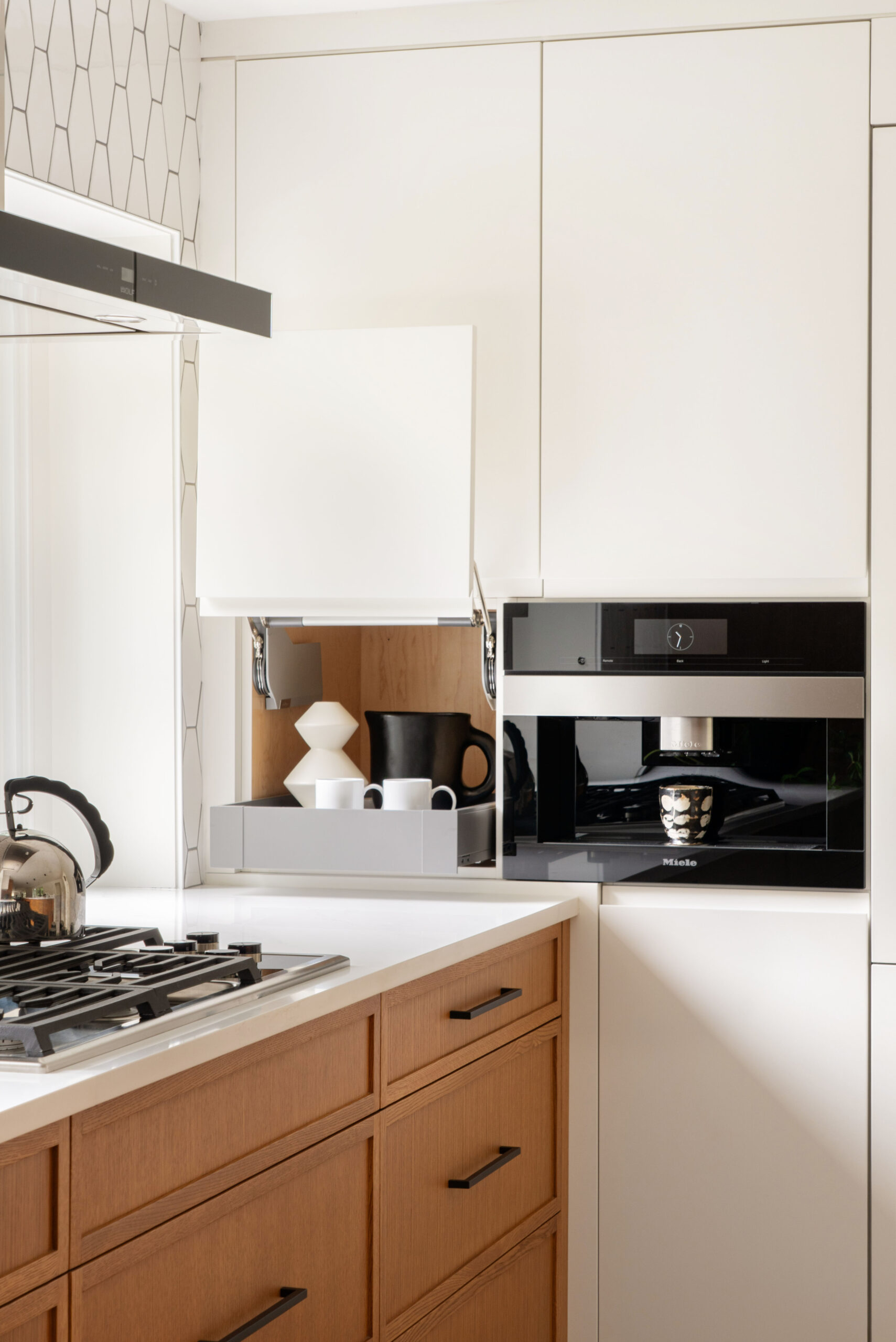 Built-in Miele coffee station and concealed cabinet bar in a bright kitchen with custom white and oak cabinetry.