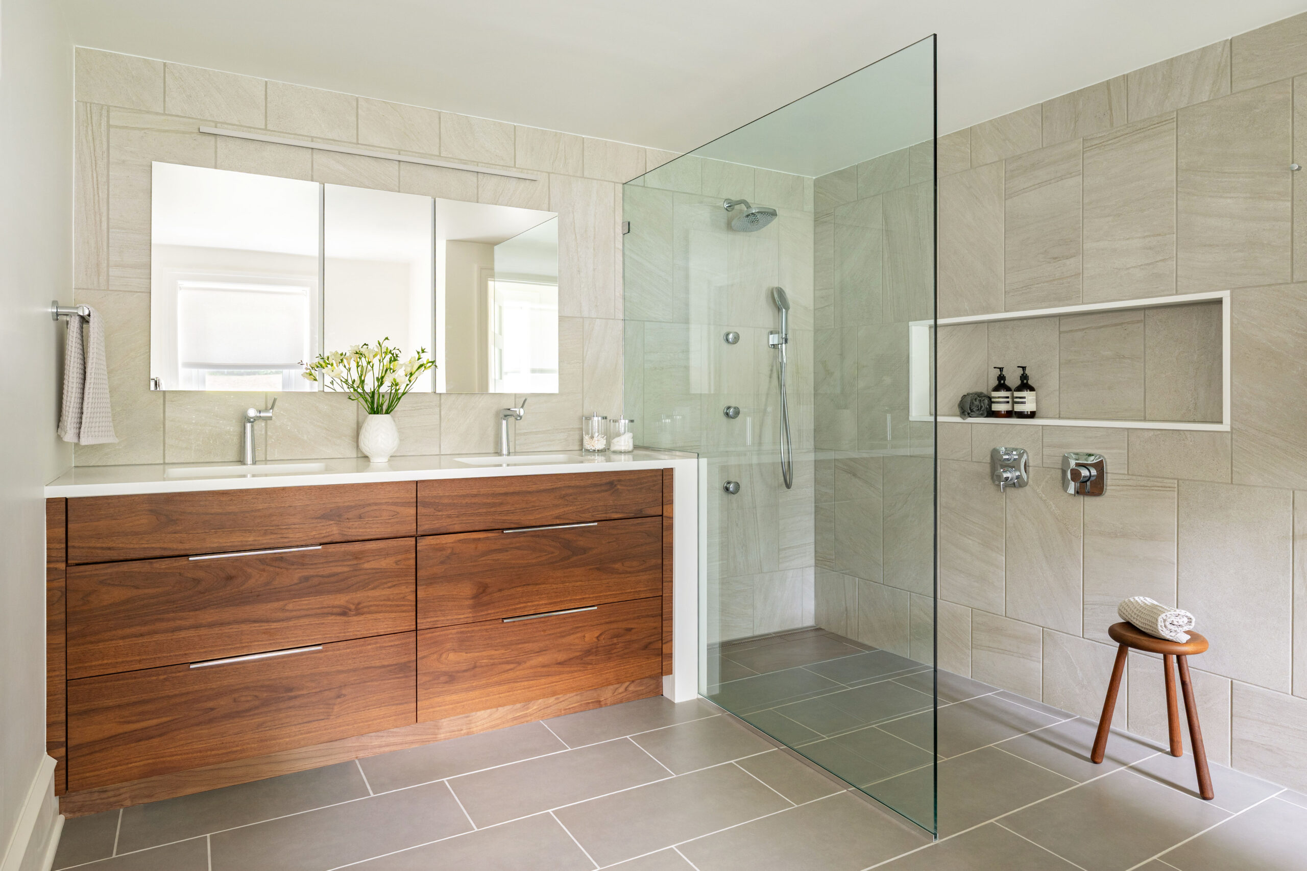 ontemporary bathroom with walnut vanity, walk-in glass shower, stone tile walls, and neutral palette.